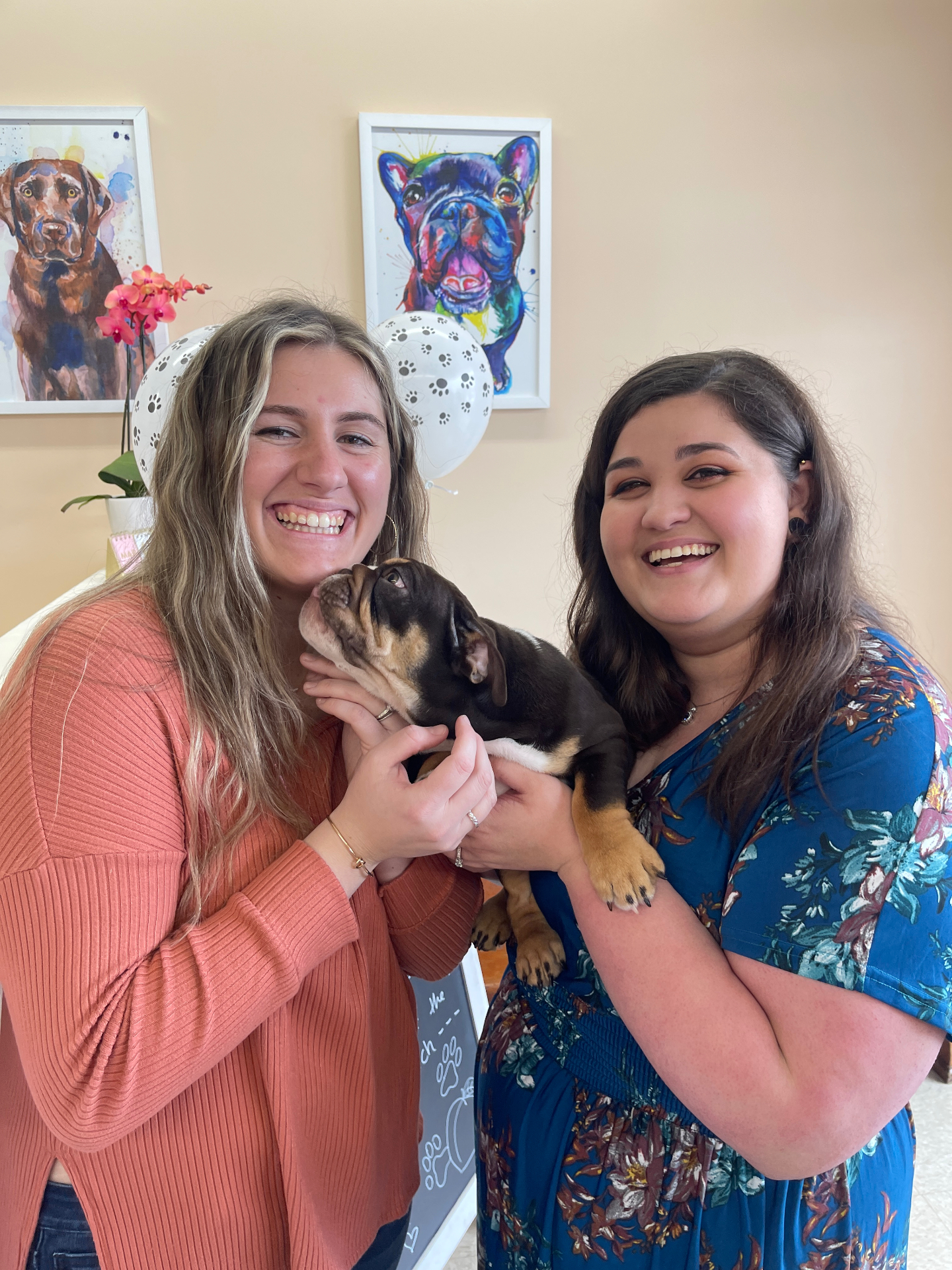 Liz and Sofia holding a French bulldog puppy in the salon lobby
